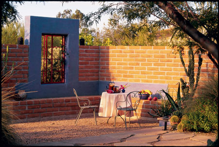 Brick walls and a periwinkle-blue faux picture window enclose an outdoor living space in the garden of this Tucson home.